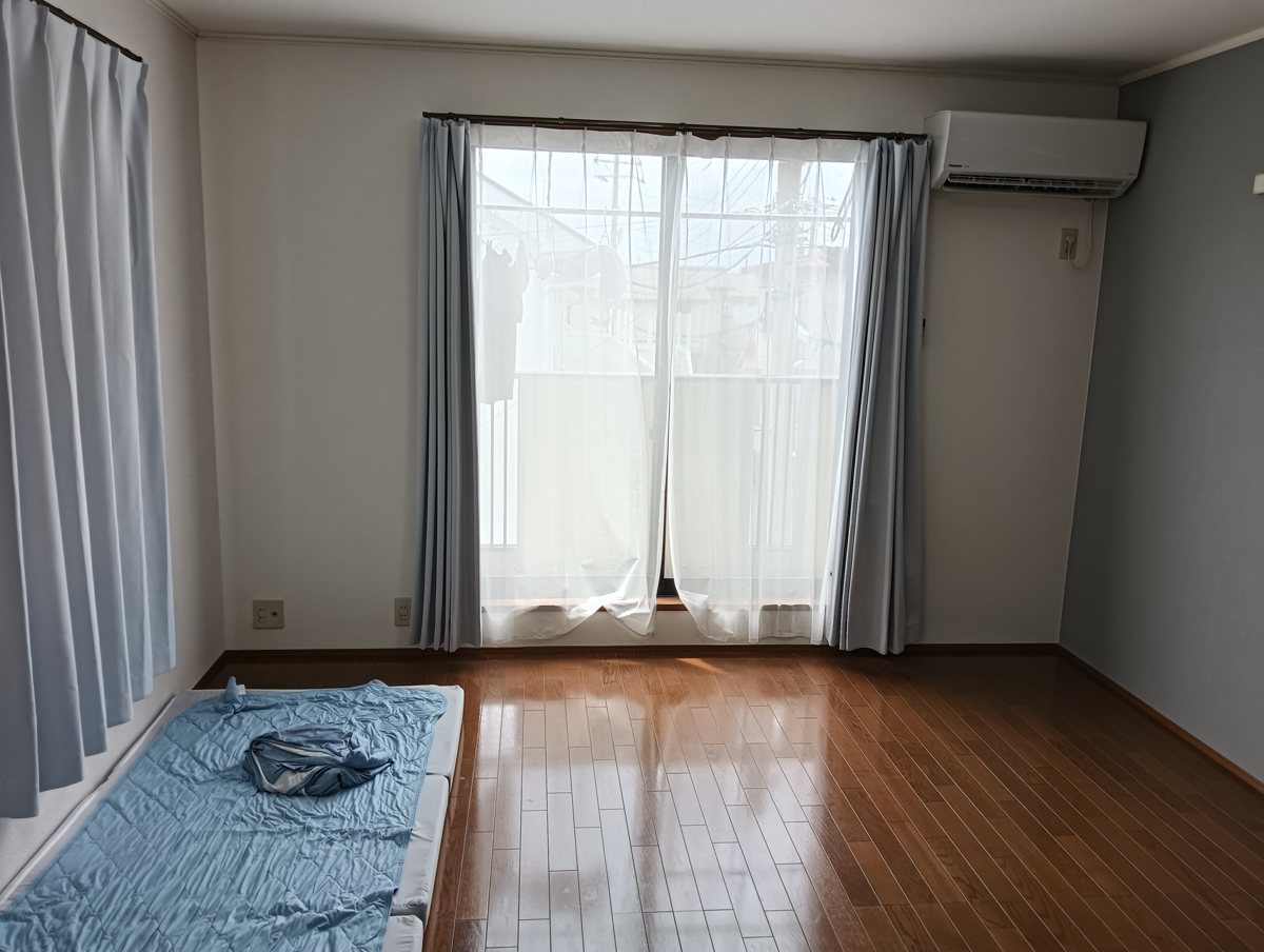 調査回答者の部屋。エアコンの下に厚手のカーテンとレースカーテンが掛かった窓がある